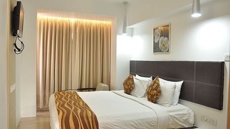 Premuim King Room with bed and a television in front of it at The Oriental Residency