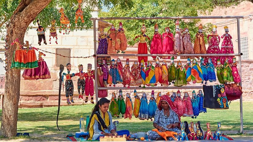 A roadside stall with two women selling traditional Indian puppets.