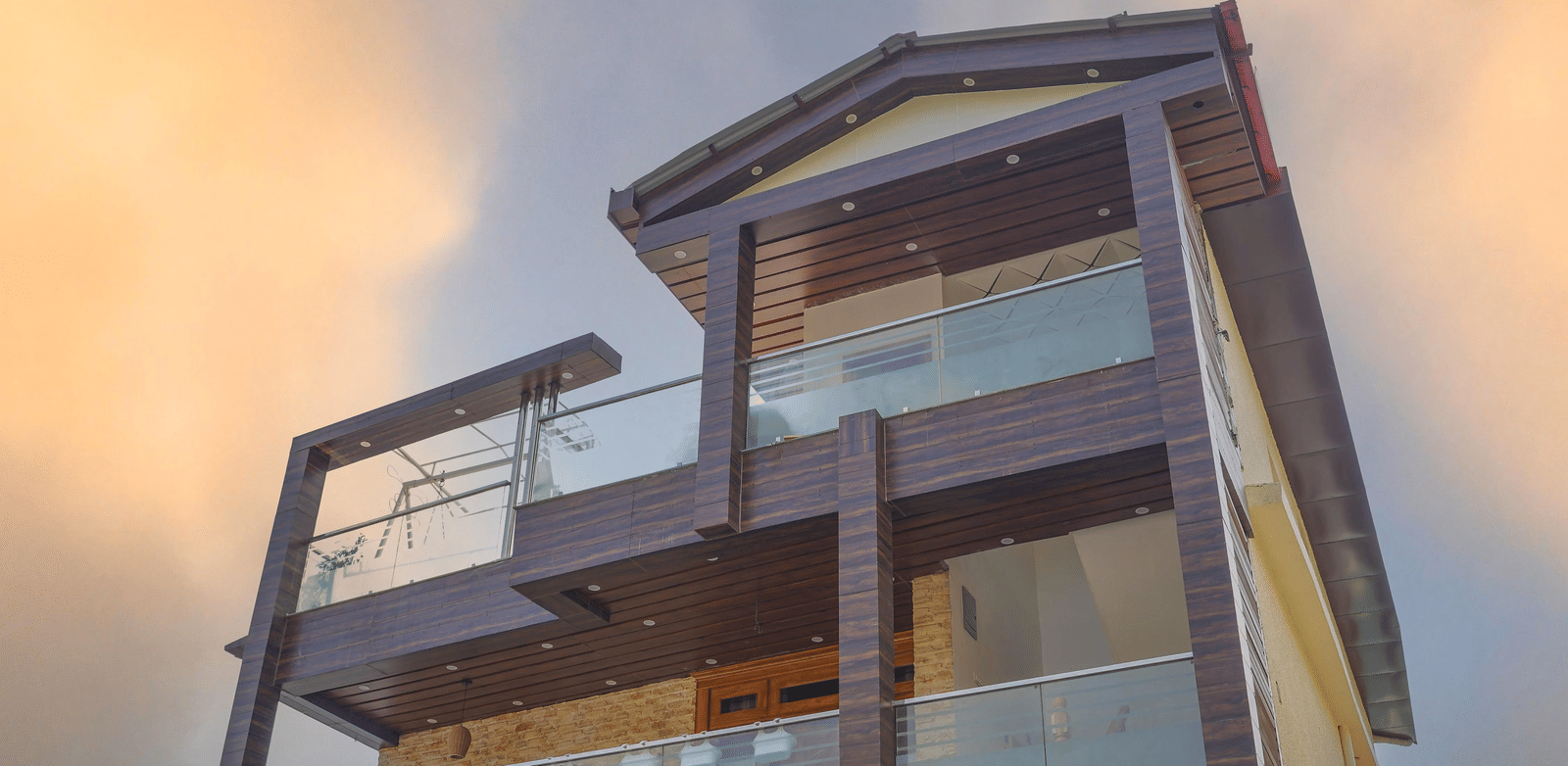 The facade of Perfectstayz Value Paradise, Mussoorie with glass balconies and wooden exterior under a cloudy sky.
