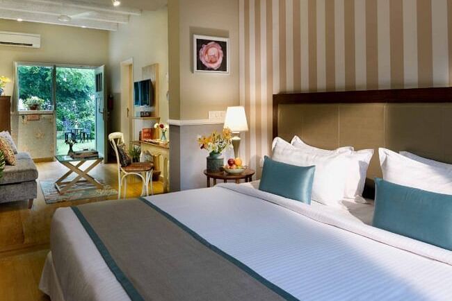 A bedroom with a large bed, wall mirror, and bedside tables with lamps at Karma Chalets. 