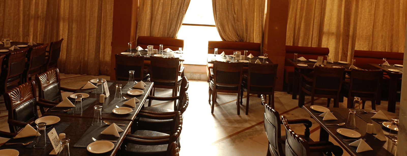 Restaurant at Hotel Gold, Panipat with arranged dining tables, chairs, and hanging lights.