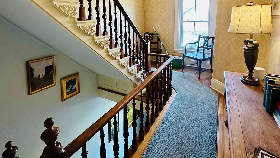 Interior hallway and staircase at Hartstone Inn showcasing classic wood banisters, neutral tones, and soft lighting