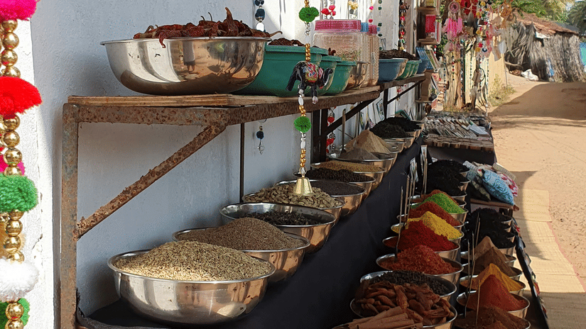 Traditional spice stall with colourful spices, herbs, and handcrafted decorative items at a local market in Goa.