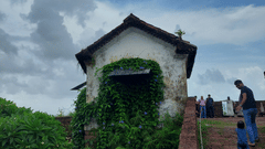 image of a hut shaped structure surrounded by green grass with a cloudy sky in the background