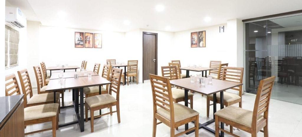 The interiors of Aranaya Restaurant at Pravasa Stay, Ahmedabad (Alba Premier), featuring well-arranged dining tables.