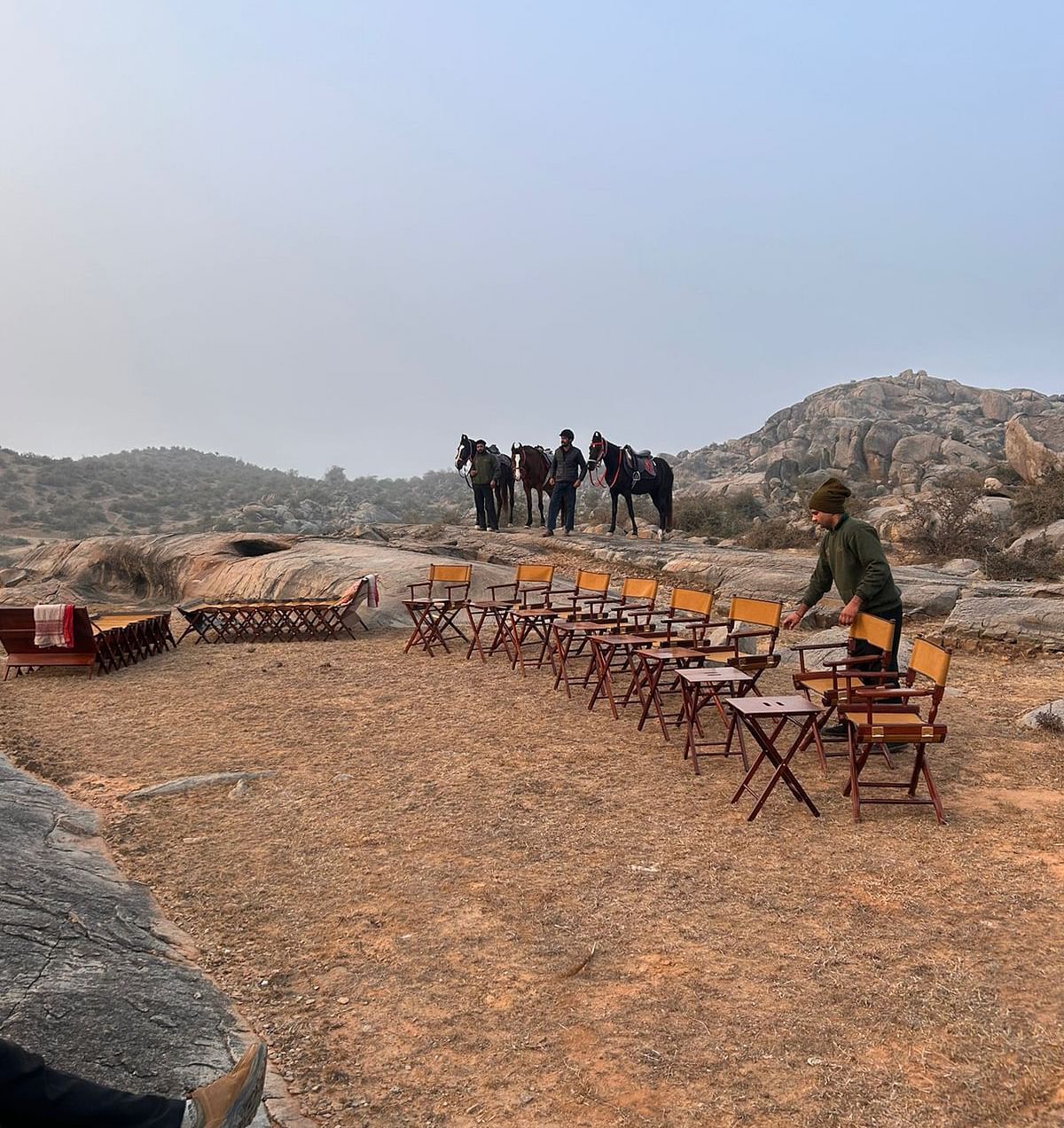 An image of horses near a seating arrangement on top of a mountain with view of the mountains - Utsav Camp Sariska