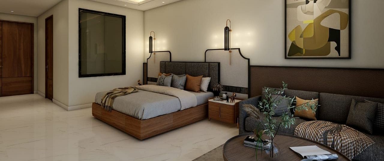 A bedroom with slightly low lighting featuring a double bed with an artistic head board along with a common seating area besides it. - Namaste Corbett