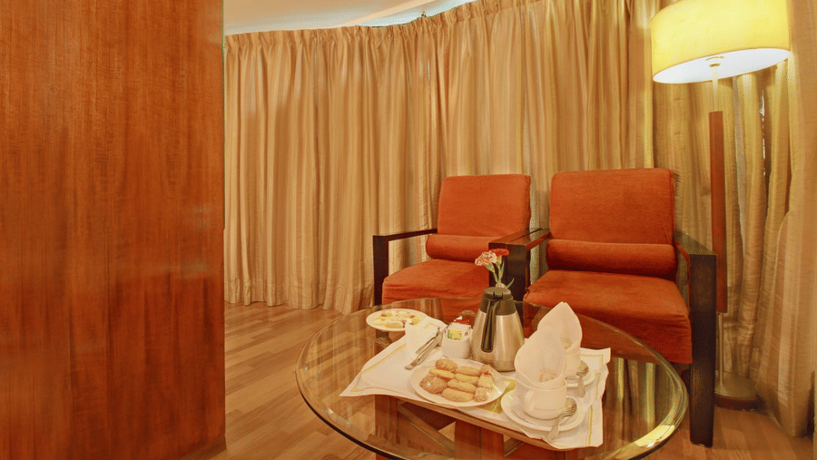 two chairs and a table kept on one side of the club royal room - Monarch Luxur Hotel, Bangalore