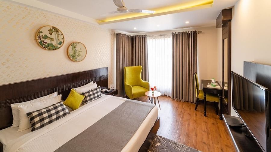 Super Deluxe Room at Rockland Hotel, CR Park, featuring a cozy bed and a chair in the corner.