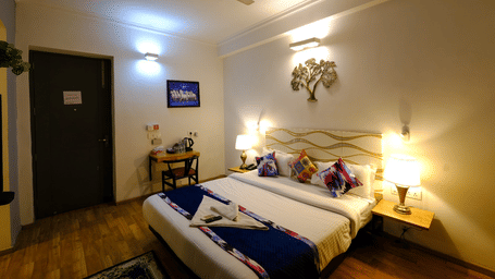 Bedroom of Lime Tree Hotels & Service Apartment Private Limited featuring twin beds with purple cushions and bedside lamps.