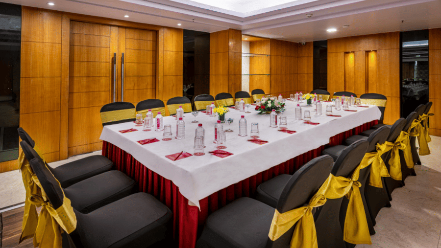 a boardroom meeting arrangement at a Banquet hall in Libra Lords Inn Jaipur with wood-panelled walls and ceiling lights