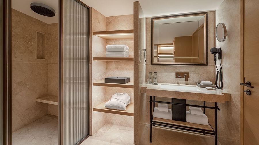 Stylish wardrobe in the corner of a suite room at The Residency Chennai, featuring shelves for storage and a wall-mounted mirror.
