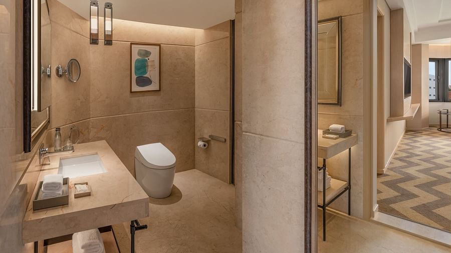 Modern suite room bathroom at The Residency Chennai, featuring a sleek sink and a separate glass-enclosed bathing area.