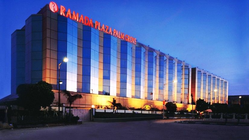 Facade view during twilight with the lights on and signage lit - Hotel Ramada Plaza Palm Grove.