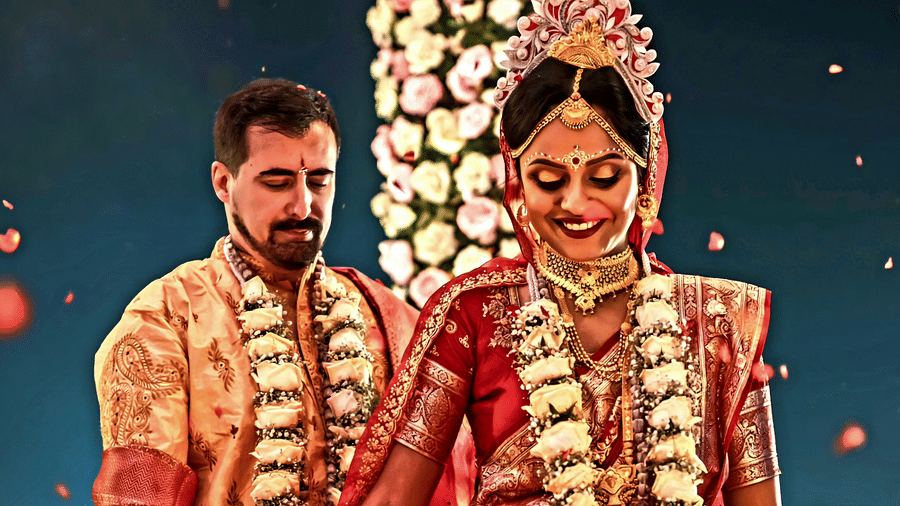A bride and groom in traditional South Indian wedding attire walking together at an outdoor wedding ceremony at Vedic Village Spa Resort with floral garlands and guests in the background.