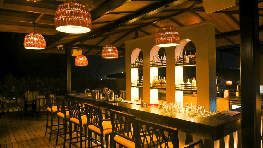Indoor bar at The Terrace, Aloha on the Ganges, Rishikesh, featuring backlit shelves, high bar stools, and warm pendant lighting.