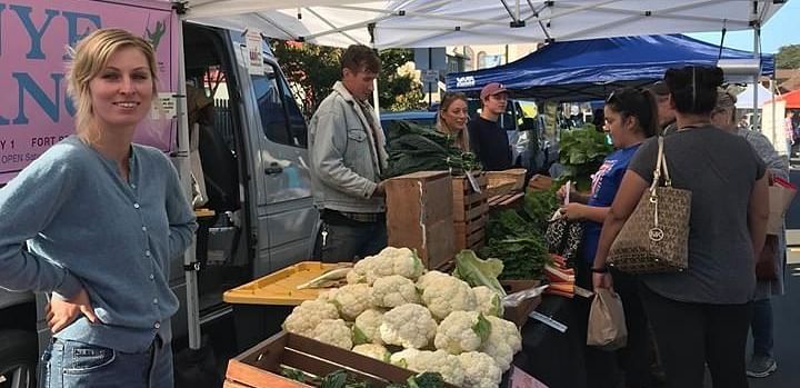 A lady smiling and standing in front of a table set with cauliflower.