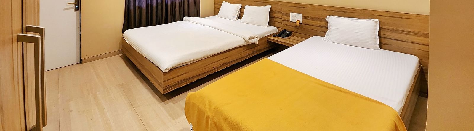Overview of Triple Premium Room at The Kanila Resort featuring a bed with a gray headboard and white sheets and a window.