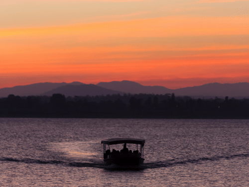 A twilight view of a boat travelling towards the camera with different hues in the sky after the sunset.