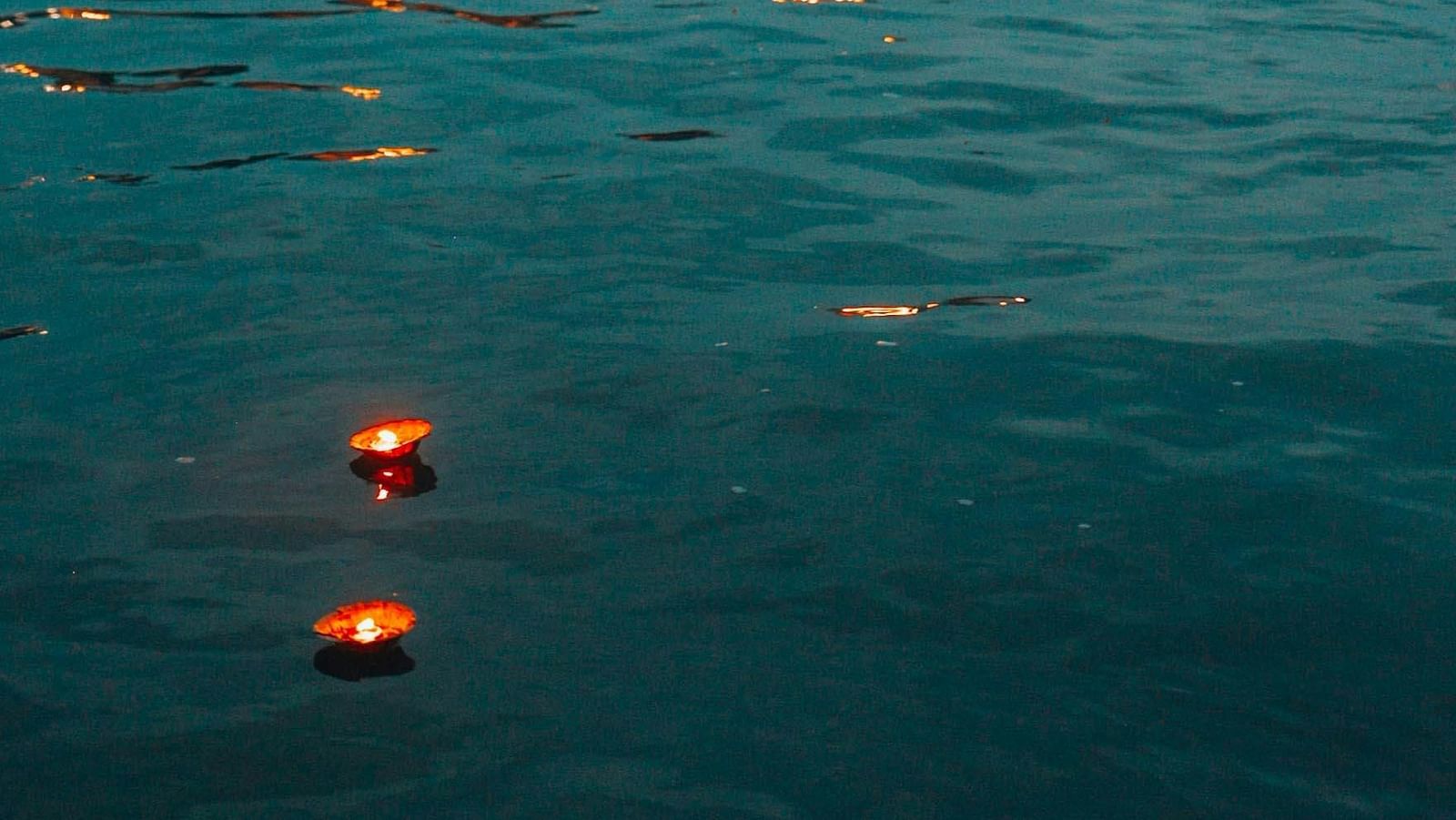 Riverside view of a town at dusk with glowing reflections on the water.