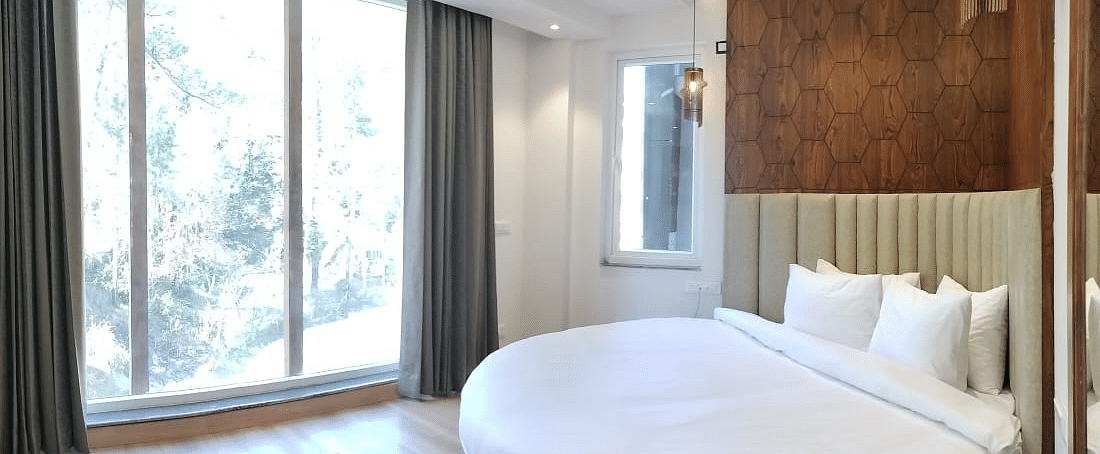 A large bed next to a large window in Deluxe Non-view Room at DLS Ark Holiday Inn, Banikhet.