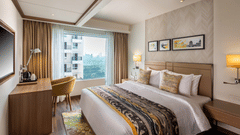 Spacious suite room at Royal Hometel Suites, Dahisar, Mumbai with large bed, work desk, and city-facing window.