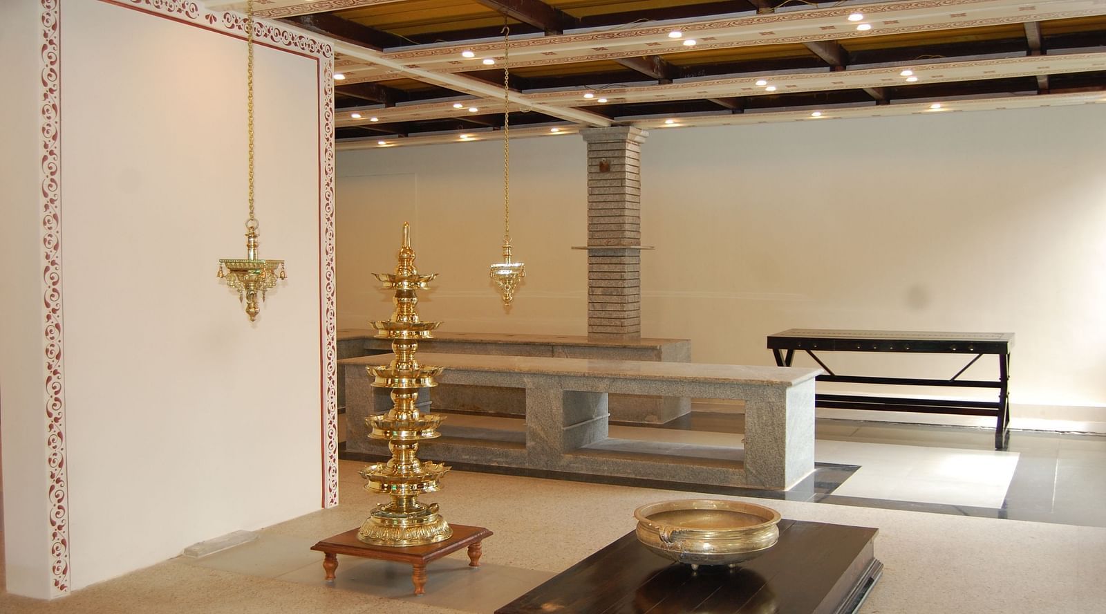 image featuring a tall brass structure for oil lamp along with concrete platforms at Hoysala Village Resort, Hassan