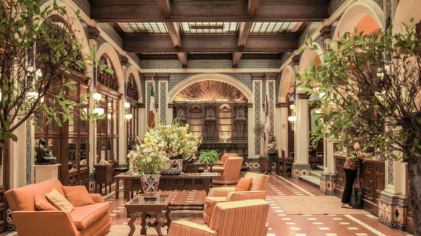A lobby area featuring neatly arranged cushioned sofas, adorned with an abundance of decorative plants