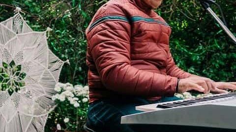 Musician playing a keyboard and singing at an outdoor event at Karma Chalets