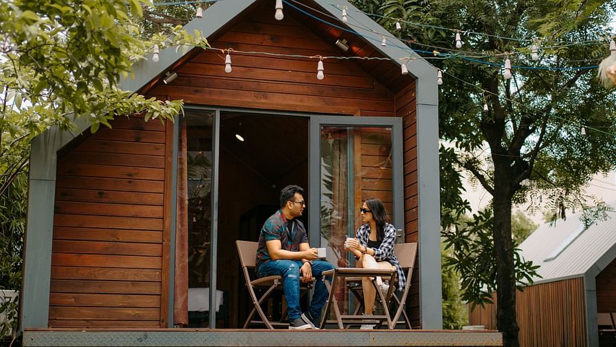 A couple sits outside the cottage room, chatting and enjoying the surrounding natural view at Crescent Spa & Resort, Indore