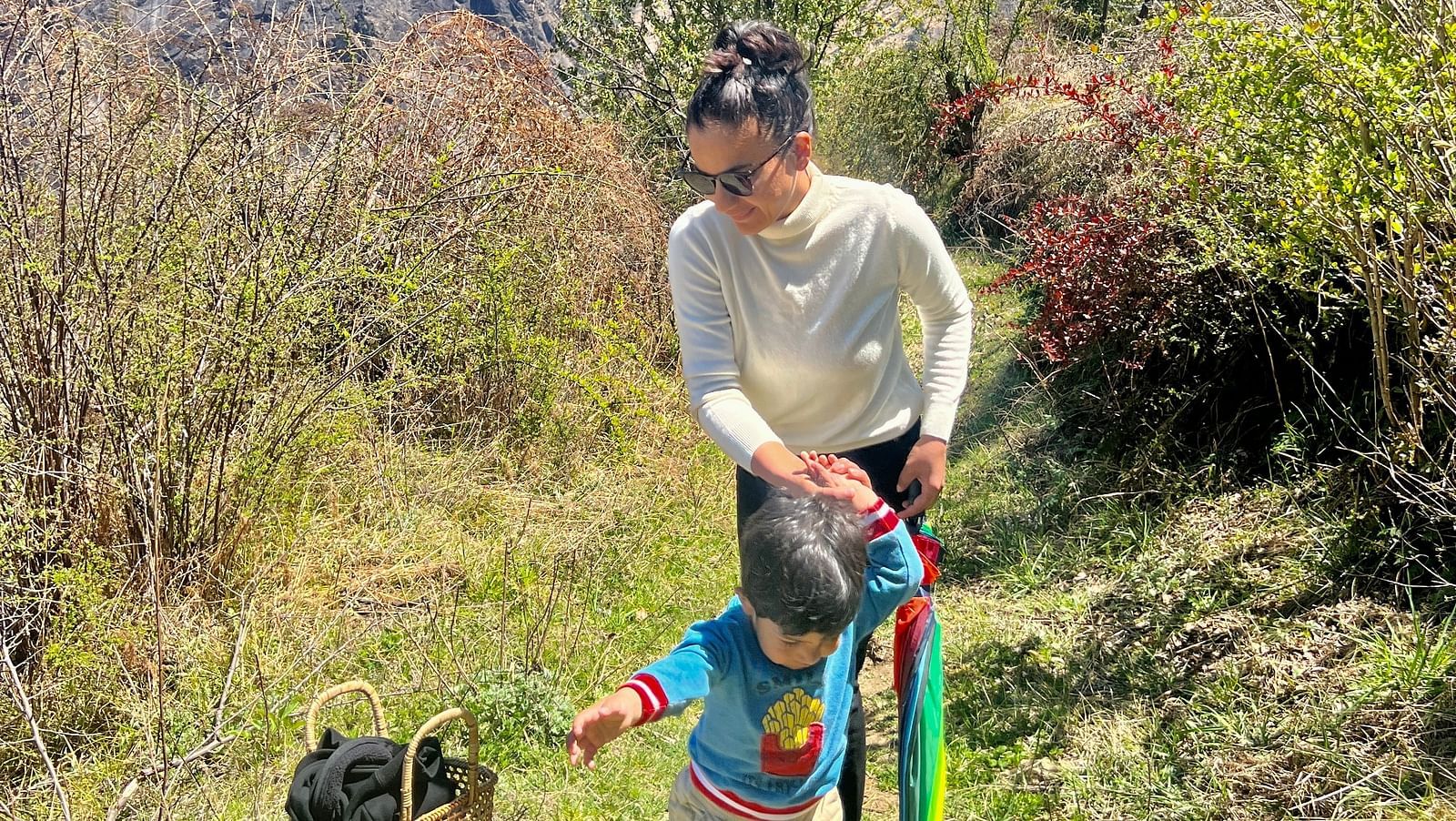 Image of  lady and a child walkin with snow capped mountians in the background | Faraway Cottages, Auli