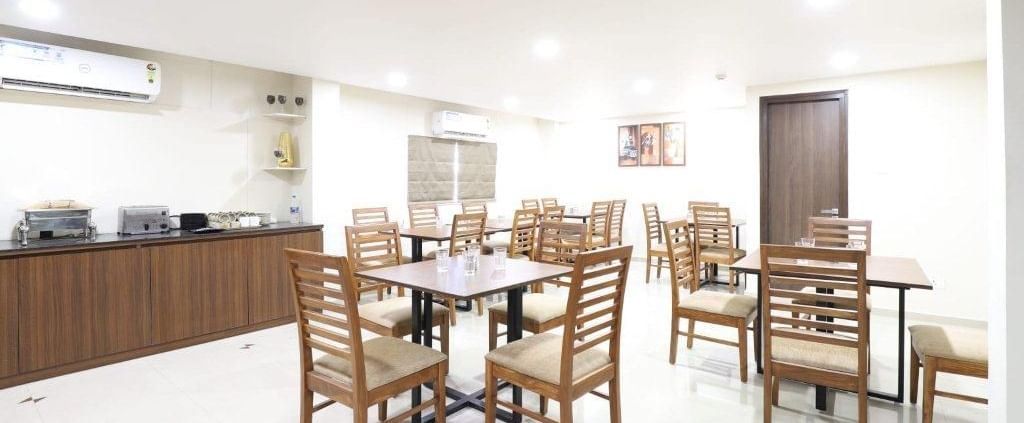Corner view of the restaurant in a brightly-lit indoor space at Pravasa Stay, Ahmedabad (Alba Premier).