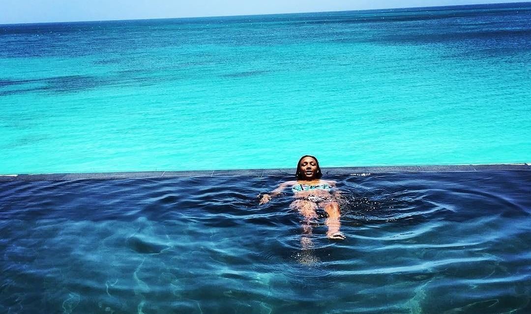 A person floats in clear blue ocean water under a bright sky.