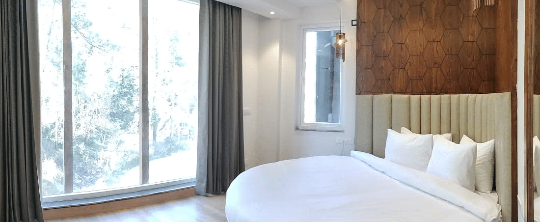 A large bed next to a large window in Deluxe Non-view Room at DLS Ark Holiday Inn, Banikhet.