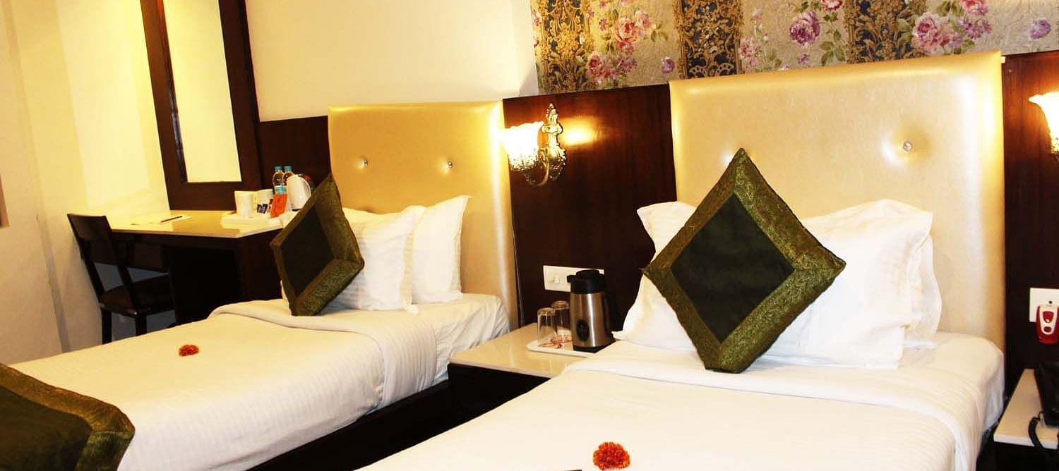 A cosy hotel room with two single beds, beige headboards and a work desk - TGI Apple Inn, Jaipur 