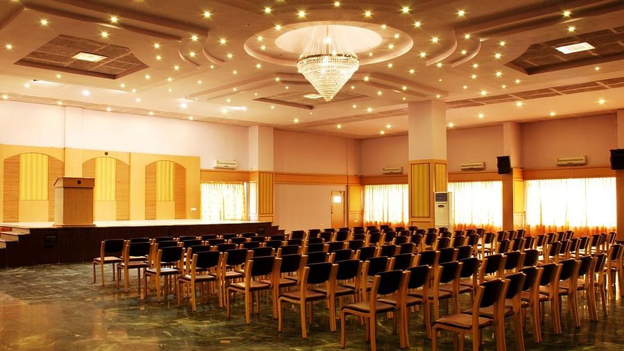 A view of a banquet hall at Paradise Isle Beach Resort, Udupi with a chandelier and a theatre style seating arrangement