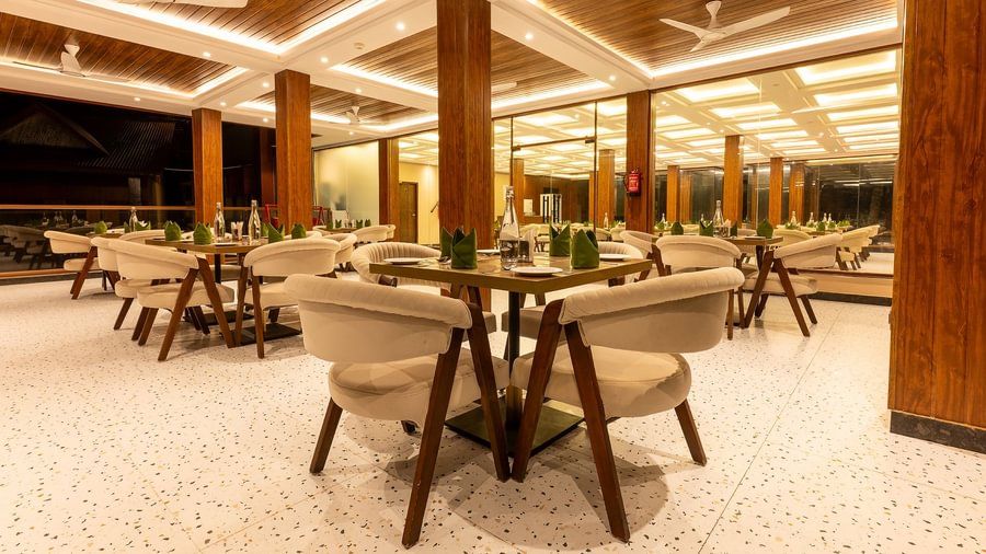 The resort's restaurant interior with light furniture, wood-panelled ceilings, and warm evening lighting.