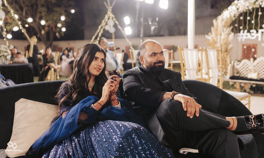 Couple enjoying a relaxed moment at an evening wedding event with ambient lighting.
