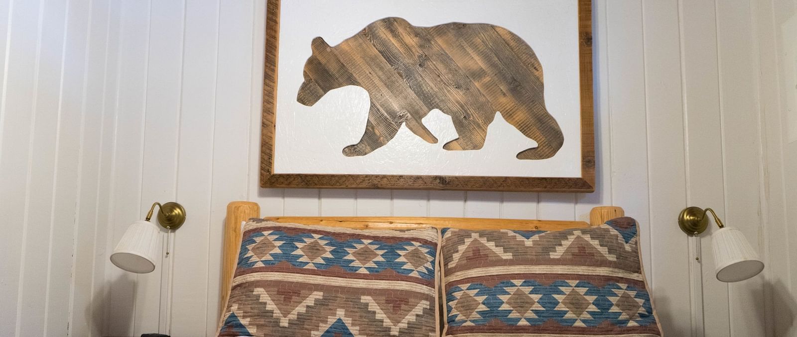 A room with a double bed and an artwork of a bear hung on the wall behind it at Shaver Lake Village Hotel.