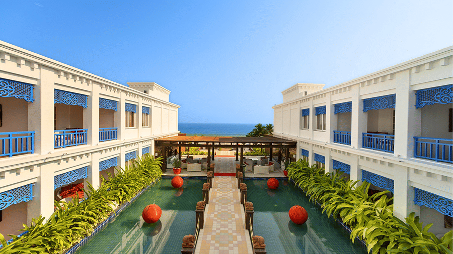 Outdoor courtyard featuring a footbridge over a decorative pool flanked by resort buildings at MAYFAIR Palm Beach Resort, Gopalpur-on-Sea.