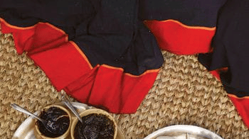 Overhead view of a local woman placing freshly made white Yomari rice dumplings onto brass plates during a festival in Nepal.