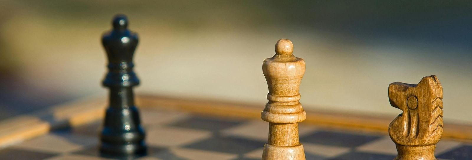 A wooden chess board with four chess pieces.