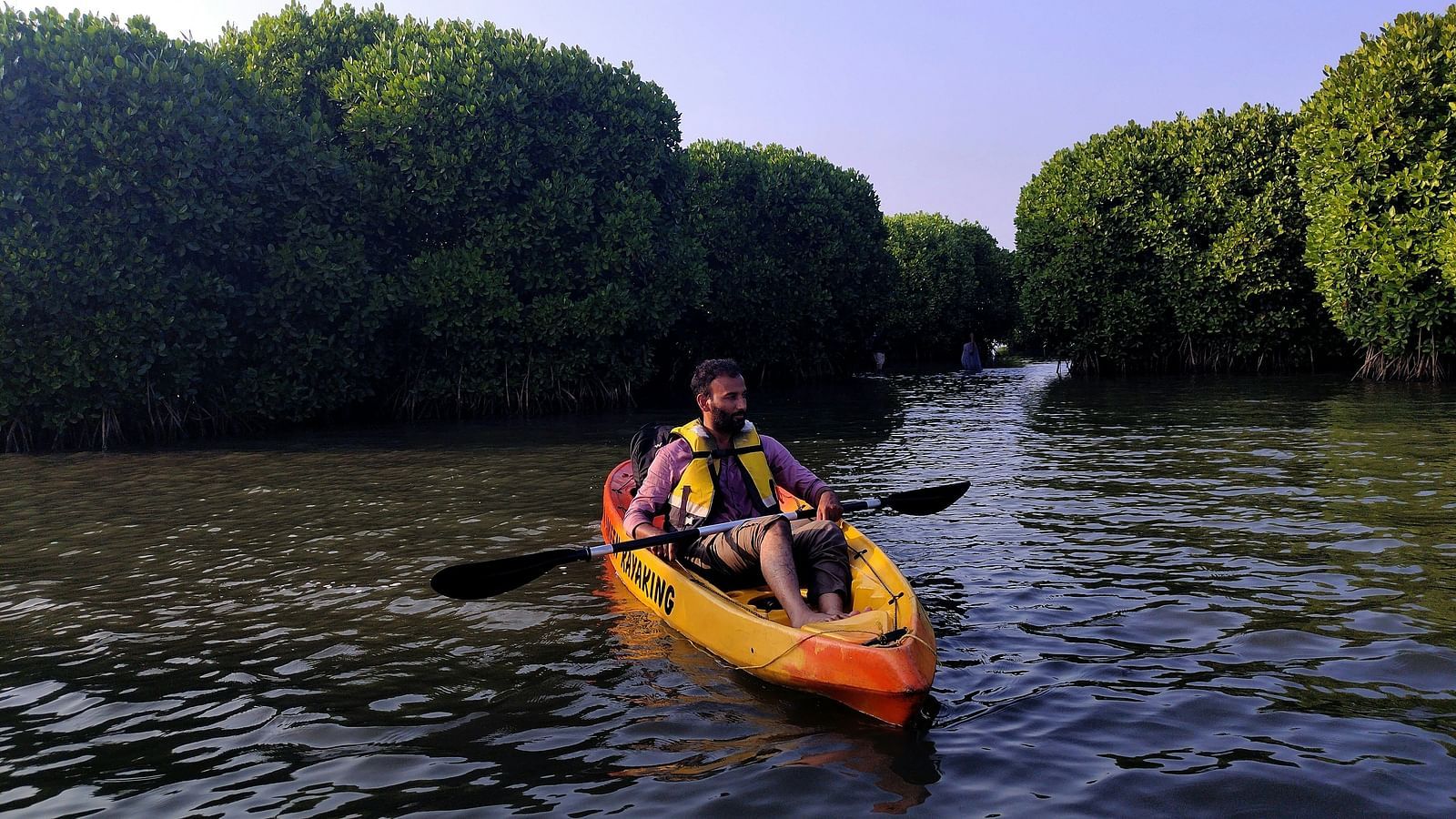 A solitary person kayaking in a waterbody as seen from front