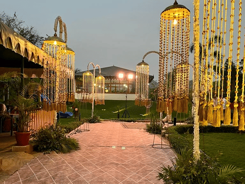 A winding path flanked by light decorations on either side, with lush green lawns stretching out alongside it