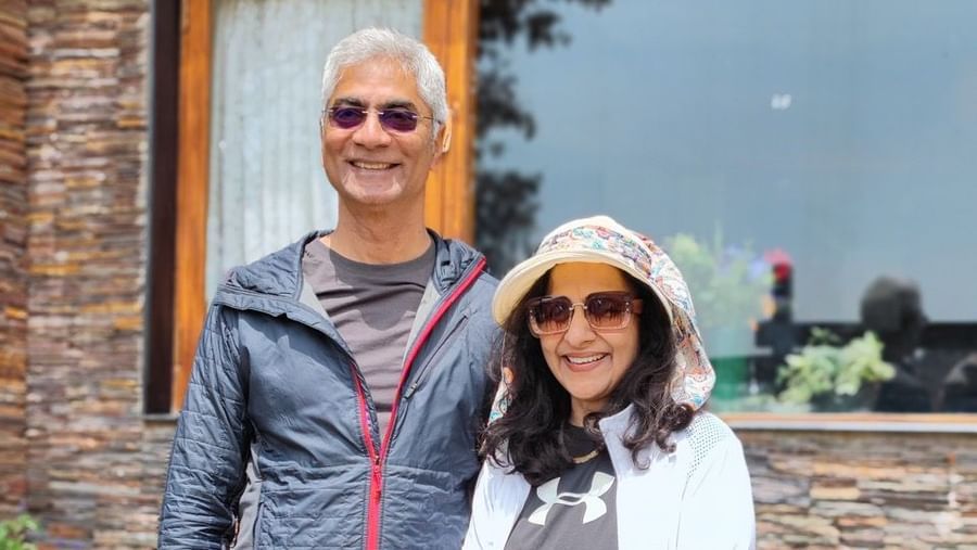 Man and woman standing and smiling in front of a glass-windowed building at the resort.