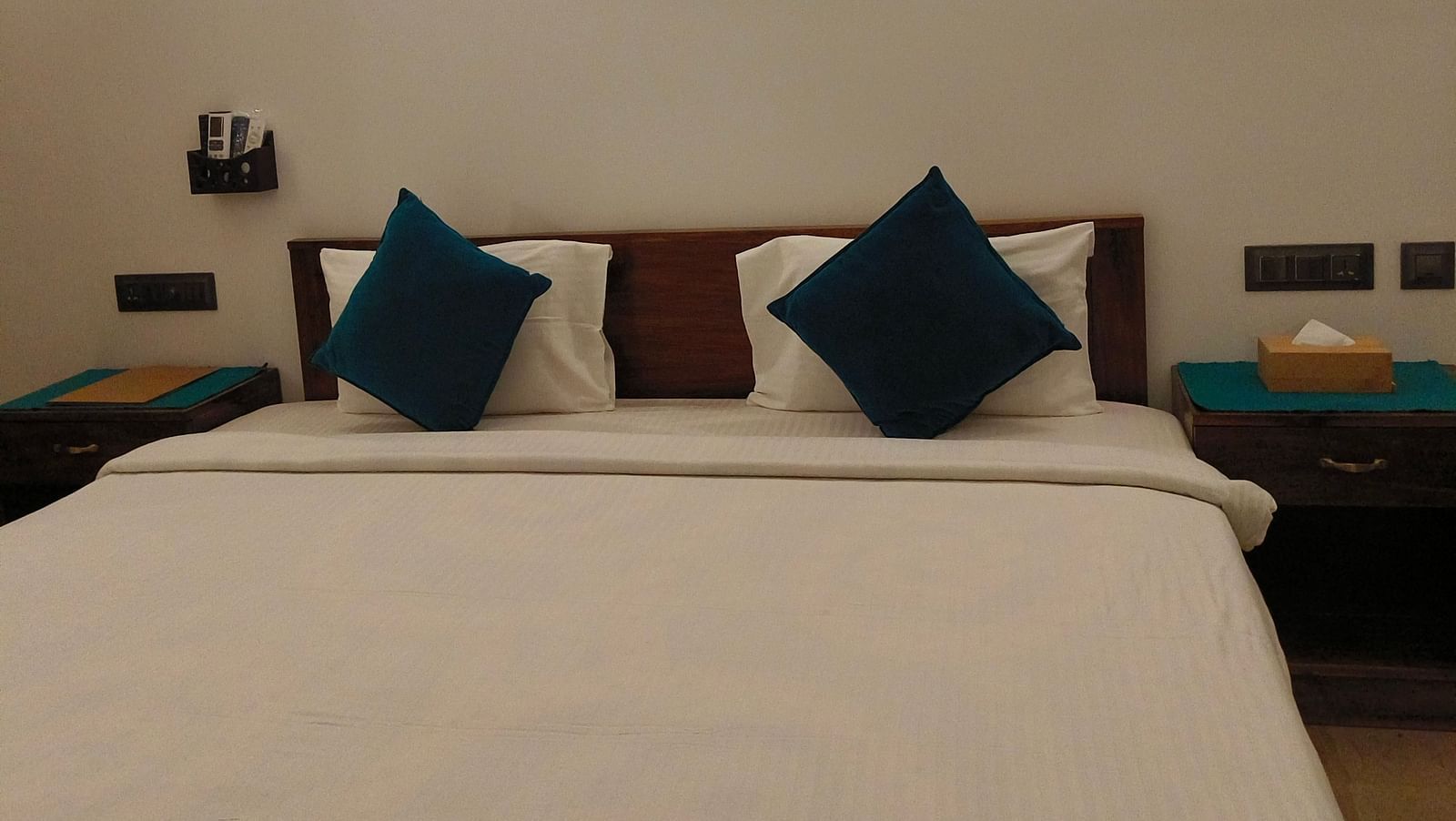 Front view of a double bed with blue pillows in 102 room at Ananda Holiday Home, Wayanad 7