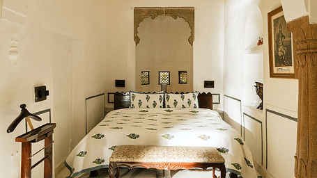 A room with a double bed and a suit hanger at Hotel Fort Barli