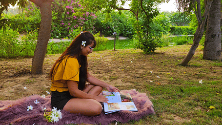 A girl sitting on the lawn reading a book - Karma Lakelands.