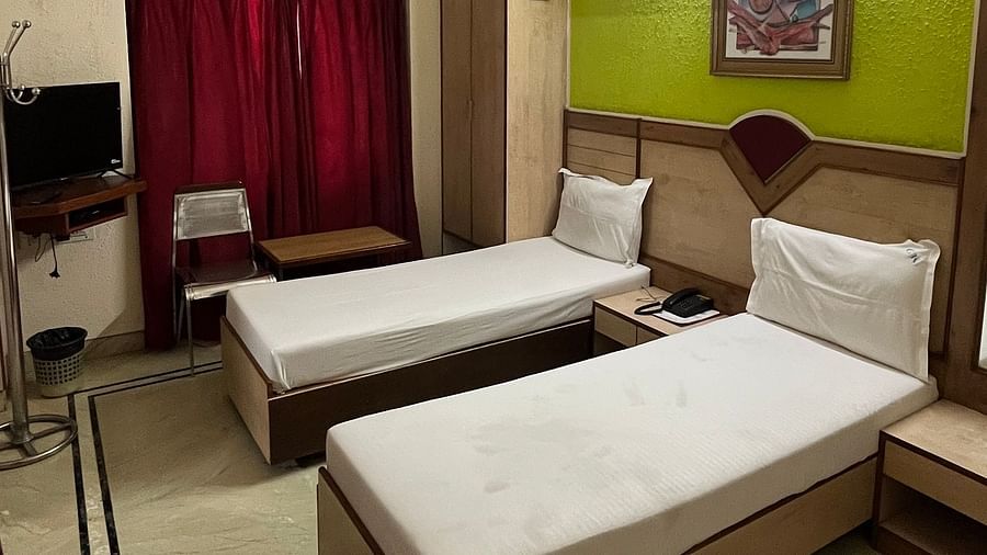 image of the superior room featuring a twin bed with plain white sheets spread at The Grand Krishna Rooms, Bengaluru