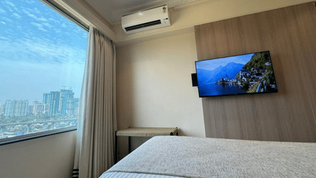 Modern hotel room with a large window view, wall-mounted TV, and cosy bedding.